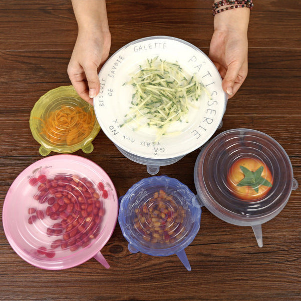 Colorful silicone lids on bowls with food on a wooden surface