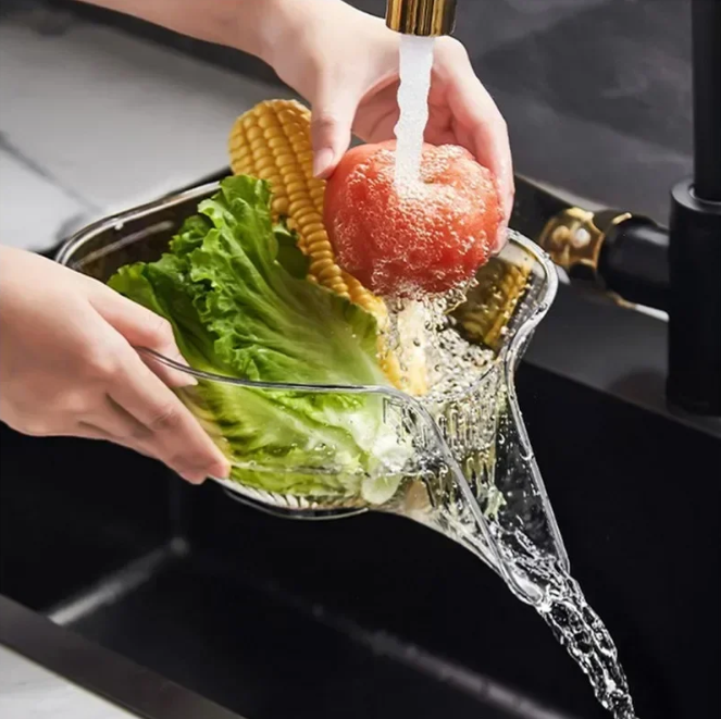 Person washing vegetables with Multi-functional Kitchen Strainer Basket under running water in a kitchen sink.