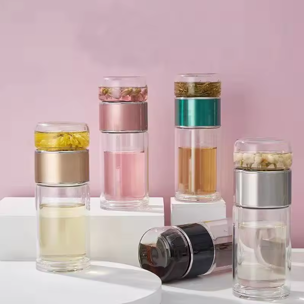Set of glass tea infusers with different colored layers on a pink background